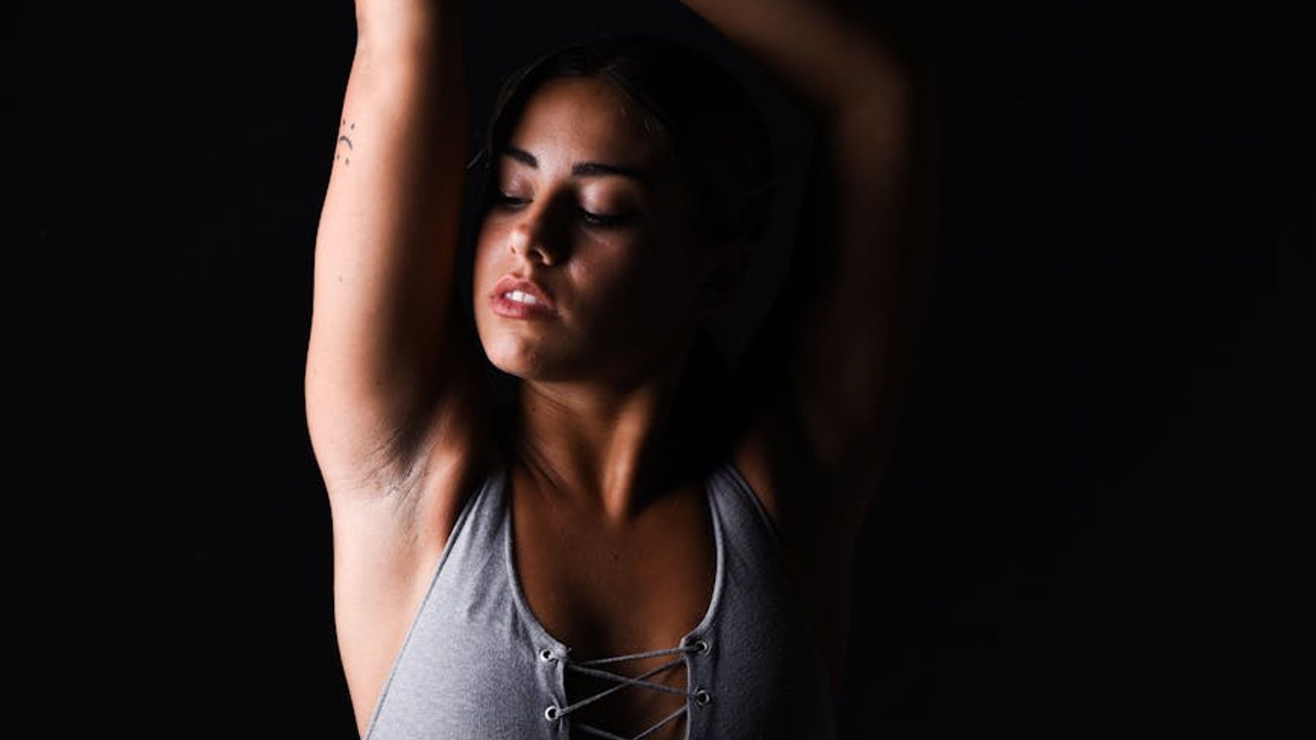 Athletic woman performing focused movement in a dark studio atmosphere.